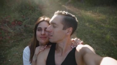 Genç aşıklar, el değmemiş ormanda yürüyüş yapıyorlar. Birbirlerine sarılıyorlar. Gün batımında güzel bir selfie çekiyorlar..