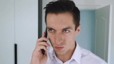 Ofis arka planında cep telefonuyla konuşan kendinden emin bir işadamı..