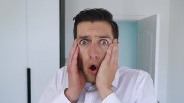 Korkak işadamı, korku ve şaşkınlık dolu bakışlarıyla kameraya bakar. Ofis geçmişinde şok olmuş bir adamın portresi.