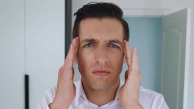 Baş ağrısı çeken yorgun bir ofis çalışanı. Beyaz gömlekli stresli iş adamı baş ağrısı ve masaj hissediyor. Rahatlamak ve acıyı azaltmak için, kapalı alanda, kapat..