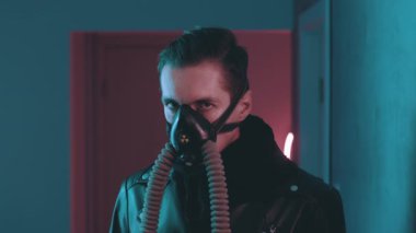Geceleri siber punk tarzında neon ışıkların üzerinden kameraya bakan solunum cihazındaki acımasız adam. Gaz maskeli tehlikeli bir erkek mavi ve pembe ışıklı arka planda