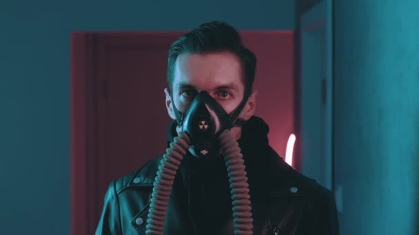Βίαιος άντρας σε αναπνευστήρα που κοιτάζει την κάμερα τη νύχτα πάνω από φώτα νέον στο στυλ του κυβερνοπανκ. Επικίνδυνο αρσενικό σε μάσκα αερίου σε μπλε και ροζ νέον φως φόντο — Αρχείο Βίντεο