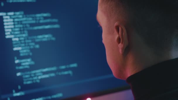Widok tylny programisty pracującego nad projektem. Portret hakera pracującego na komputerze w nocy w neonach. — Wideo stockowe
