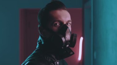 Geceleri siber punk tarzında neon ışıkların üzerinden kameraya bakan solunum cihazındaki acımasız adam. Gaz maskeli tehlikeli bir erkek mavi ve pembe ışıklı arka planda
