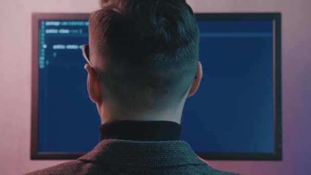 프로젝트에서 일하는 소프트웨어 개발자의 레어 뷰. 밤에 네온등을 켜고 컴퓨터에서 일하는 인간 해커의 모습. — 비디오