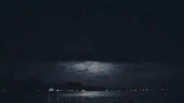 Geceleri denizin üzerinde şimşek çakar. Tropik fırtına, akşam gökyüzünde şimşekler çakıyor, gök gürültülü fırtına yaklaşıyor..