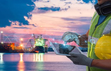 Nakliye limanındaki işçiler, akıllı lojistik, küresel ticaret ve deniz teknolojisi yeniliklerini sembolize eden, gelecekteki dijital arayüz örtüsüne sahip tablet kullanıyorlar.