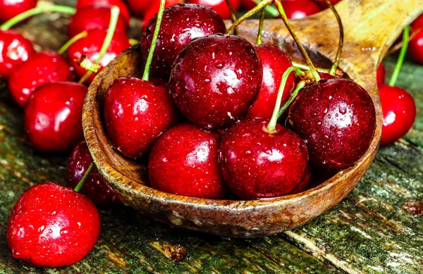 Cherries on wooden table with water drops macro background