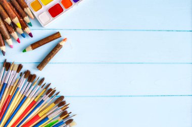 Boyalar, fırçalar ve palet mavi ahşap arka plan üzerinde. Sanatçı işyeri. Okul için banner