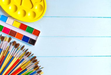 Boyalar, fırçalar ve palet mavi ahşap arka plan üzerinde. Sanatçı işyeri. Okul için banner