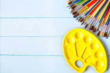 Boyalar, fırçalar ve palet mavi ahşap arka plan üzerinde. Sanatçı işyeri. Okul için banner