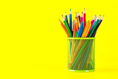 Kalemler ve kurşun kalemler sarı duvar arka plan önünde metal tutucu 