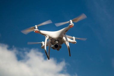 parlak mavi bir gökyüzünde gezinen beyaz drone. Yeni teknoloji