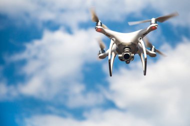 parlak mavi bir gökyüzünde gezinen beyaz drone. Yeni teknoloji