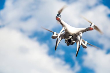 parlak mavi bir gökyüzünde gezinen beyaz drone. Yeni teknoloji