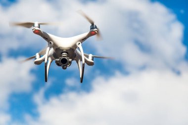 parlak mavi bir gökyüzünde gezinen beyaz drone. Yeni teknoloji