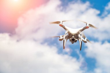 parlak mavi bir gökyüzünde gezinen beyaz drone. Yeni teknoloji