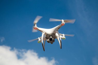 parlak mavi bir gökyüzünde gezinen beyaz drone. Yeni teknoloji