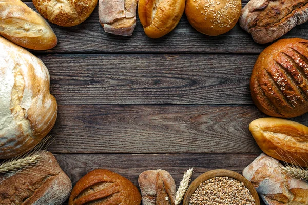 Assortiment van gebakken brood op houten tafel achtergrond, bovenaanzicht — Stockfoto