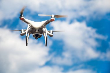 parlak mavi bir gökyüzünde gezinen beyaz drone. Yeni teknoloji