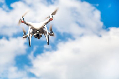 parlak mavi bir gökyüzünde gezinen beyaz drone. Yeni teknoloji