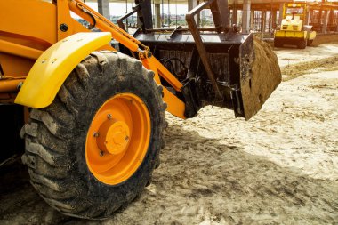 Buldozer hareket eder ve emban üzerinde toprak ve moloz yayılır