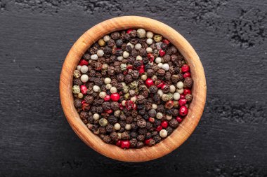 Bir biber seti. Farklı tip biber kolajı, siyah, beyaz, pembe ve tüm baharatlı biber, kurutulmuş kırmızı biber. Üst görünüm. Siyah bir arka planda. Metnin için boş yer.