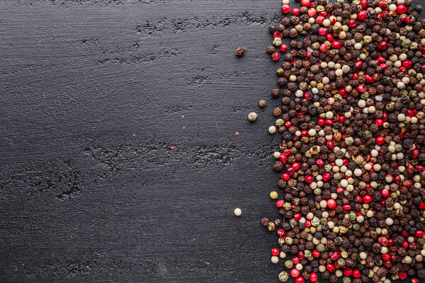 A set of peppers.Collage of different type pepper, Black ,white, pink and allspice peppercornsr, dried chili pepper.Top view. On a black background. free space for your text.