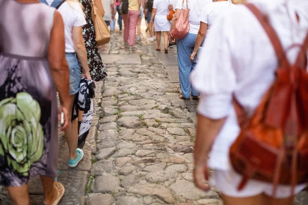 A lot of people are walking along an old cobbled street. Italy, Calabria, Tropea. Sightseeing group. Back view