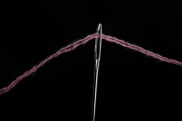 Siyah bir sırt üzerinde yün iplik ile büyük bir iğne gözü ile İğne