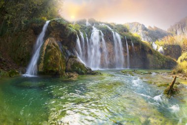Plitvice Waterfalls in Croatia is one of the famous famous places in Europe, very beautiful. The jets of water on the background of autumn forests at sunrise are very picturesque clipart