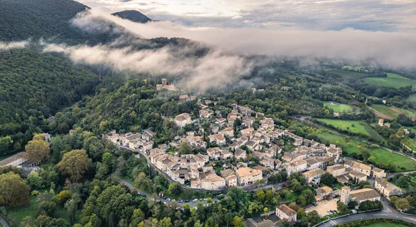 Fransa 'nın Mirmande köyünün havadan görünüşü sabah sisi ile çevrili güzel ortaçağ kasabası yemyeşil orman ve kırsal arazi yumuşak sisli gökyüzü altında tarihi mimari