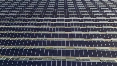 Modern greenhouse designed for growing fresh vegetables, equipped with roof-mounted photovoltaic solar panels providing renewable energy, sustainable agriculture technology, and eco-friendly food pro