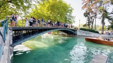 Annecy, France - 10 August 2025: Love Bridge in Annecy with tourists taking photos and boats passing underneath, showcasing the scenic canal, historic architecture, and lively atmosphere of the city.