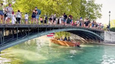 Annecy, France - 10 August 2025: Love Bridge in Annecy with tourists taking photos and boats passing underneath, showcasing the scenic canal, historic architecture, and lively atmosphere of the city.