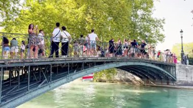 Annecy, France - 10 August 2025: Love Bridge in Annecy with tourists taking photos and boats passing underneath, showcasing the scenic canal, historic architecture, and lively atmosphere of the city.