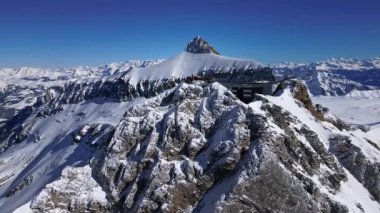 People Walking Across the Suspension Bridge on Glacier 3000 with a Cable Car Passing in the Background, and the Peak Walk in the Swiss Alps.