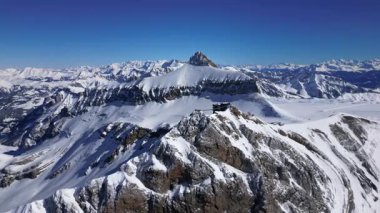 People Walking Across the Suspension Bridge on Glacier 3000 with a Cable Car Passing in the Background, and the Peak Walk in the Swiss Alps.