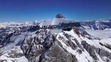 People Walking Across the Suspension Bridge on Glacier 3000 with Cable Car Station and Peak Walk in the Swiss Alps.