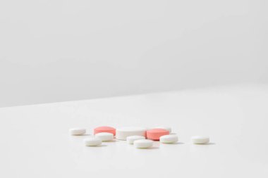 Beyaz ve pembe hapların bir sürü kopya alanı olan temiz beyaz bir yüzeyde yan görünümü