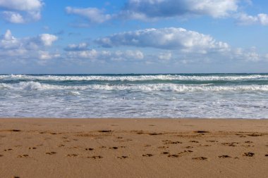 Kumda dalgalar ve ayak izleri olan boş bir sahil, seyahat ve tatil konsepti.