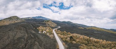 Beautiful aerial view on the empty road to Etna volcano that can be seen on the horizon. clipart