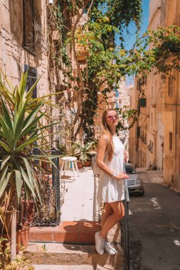 Beautiful girl in a white dress exploring Malta island near Valletta and Marsaxlokk village.  clipart
