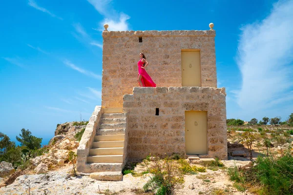 Okyanusun cliff house üstünde yürüyen uzun pembe elbiseli seksi kız. Başarılı yaşam. 