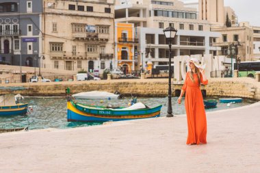 Valletta, Malta. 20 Mayıs 2018. Malta Adası üzerinde demirledi tekne tarafından yürüyüş kırmızı elbiseli güzel kız. 