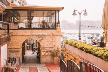 20 Mayıs 2018. St. Julian. Malta. Güzel eski şehir, St. Julian renkli tekneler, bay, mesire ve bir kedi ve bir balık ile bir balıkçı heykeli ile Malta Adası.