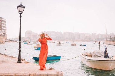 Valletta, Malta. 20 Mayıs 2018. Malta Adası üzerinde demirledi tekne tarafından yürüyüş kırmızı elbiseli güzel kız. 