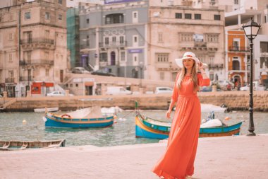Valletta, Malta. 20 Mayıs 2018. Malta Adası üzerinde demirledi tekne tarafından yürüyüş kırmızı elbiseli güzel kız. 