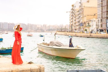 Valletta, Malta. 20 Mayıs 2018. Malta Adası üzerinde demirledi tekne tarafından yürüyüş kırmızı elbiseli güzel kız. 
