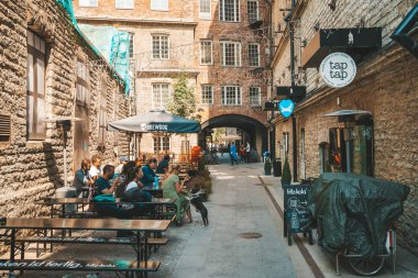11 Haziran 2018. Tallinn Estonya sokaklarında açık sokak restoran. Rahat sandalyeler ve masalar bir tabloda bir şampanya şişesi ile eski şehir ayakta.